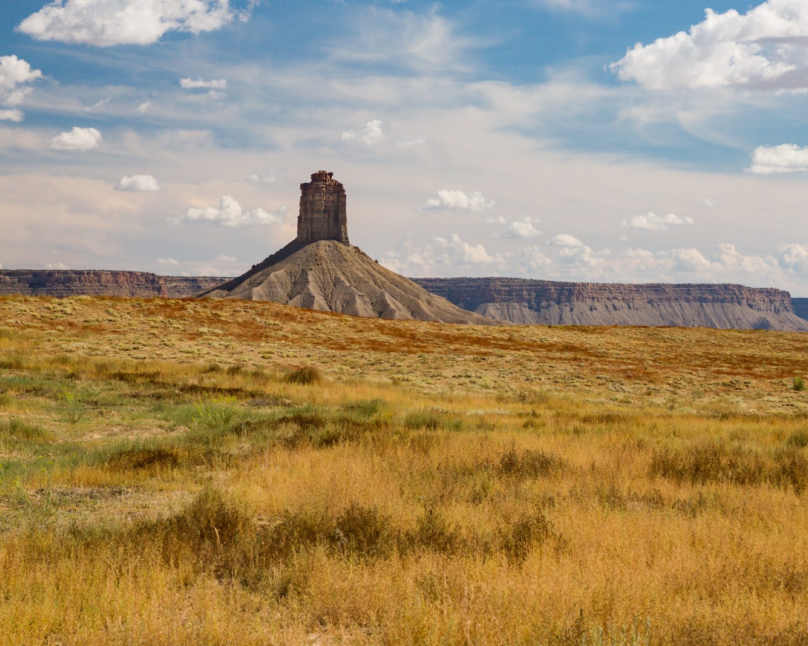 A butte rising over open high-desert grassland in Southwest Colorado