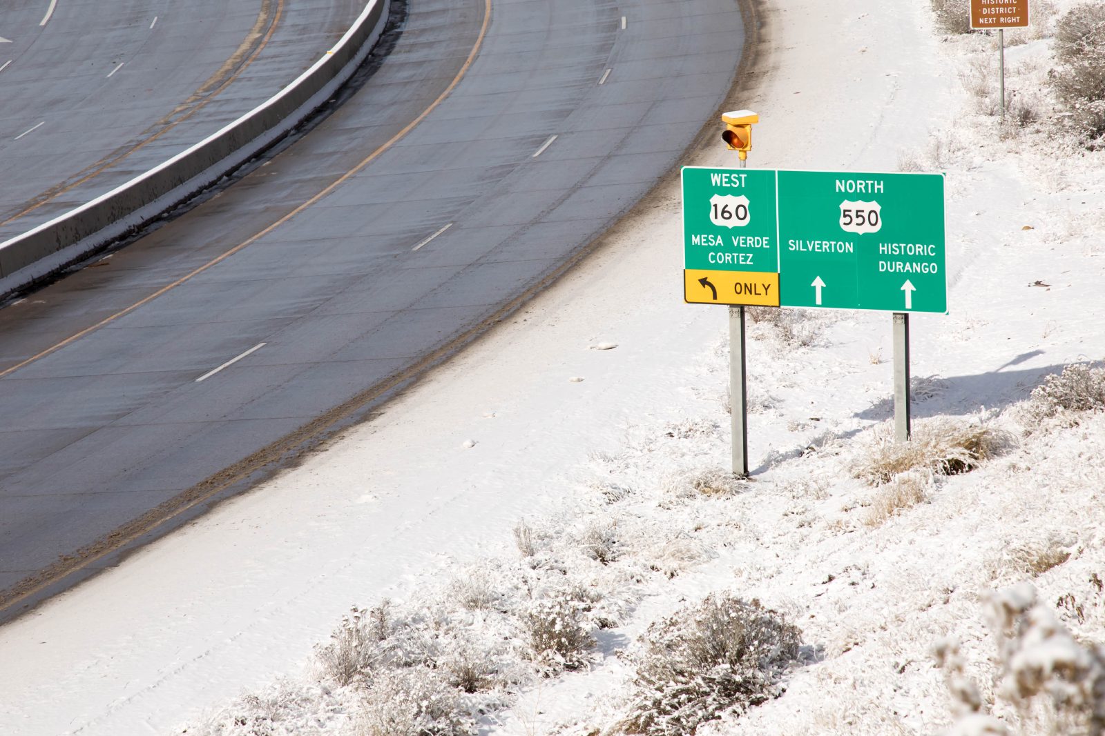 Highway signs for Mesa Verde, Cortez, Silverton, and Durango along a snowy Southwest Colorado road