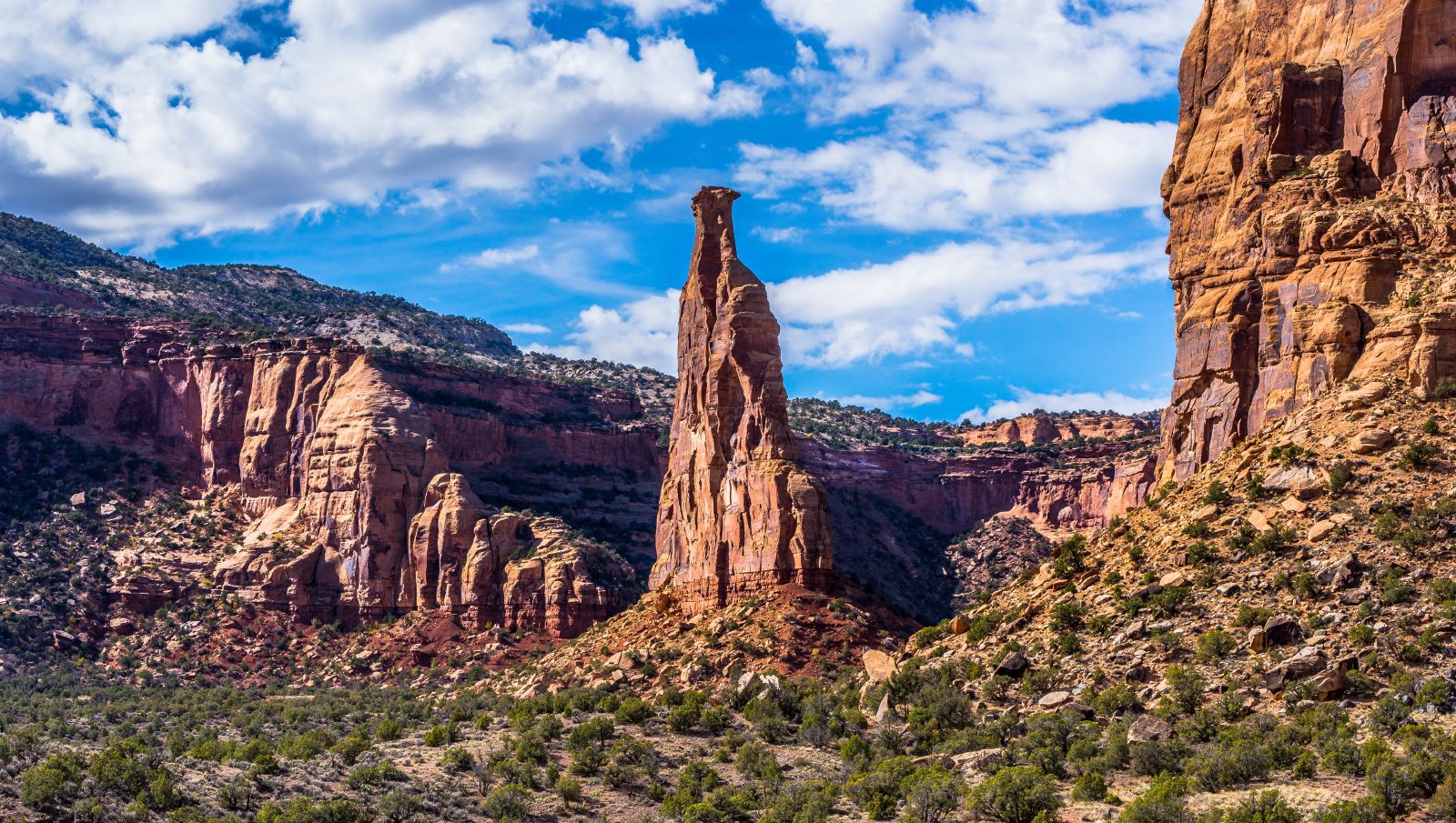 Red rock canyon with a tall sandstone spire under a blue sky