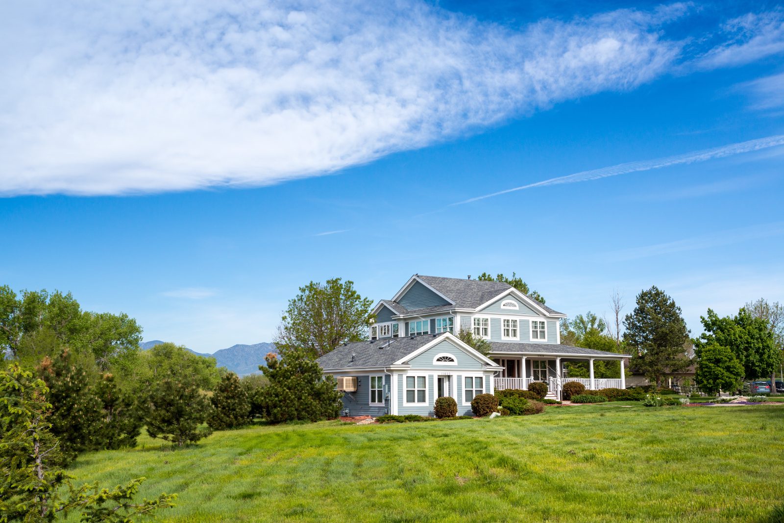 Large home on a green lawn under a blue sky